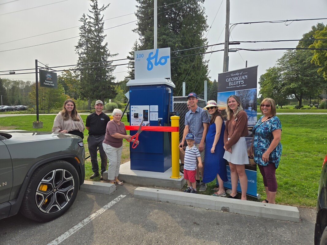 Group of people standing in front of new EV fast charger for ribbon cutting at Sarawak Park 
