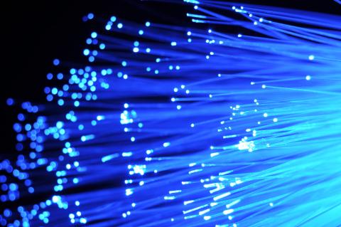 Extremely zoomed in picture of fibre optic cables.  The cable are blue and bright with light.
