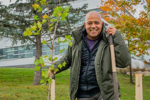 Selwyn Hicks stands in front of the Administration Building during a tree planting event in 2022. 